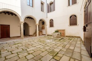 Ein Innenhof mit Steinboden, Bögen und einer Tür.