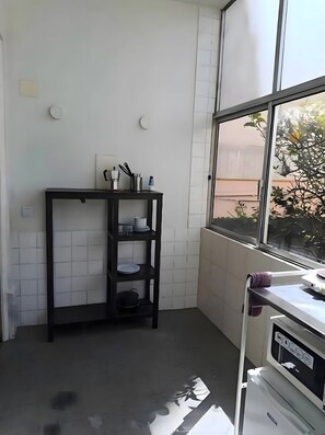 Una cocina con un estante negro, una ventana con vistas y un electrodoméstico blanco.