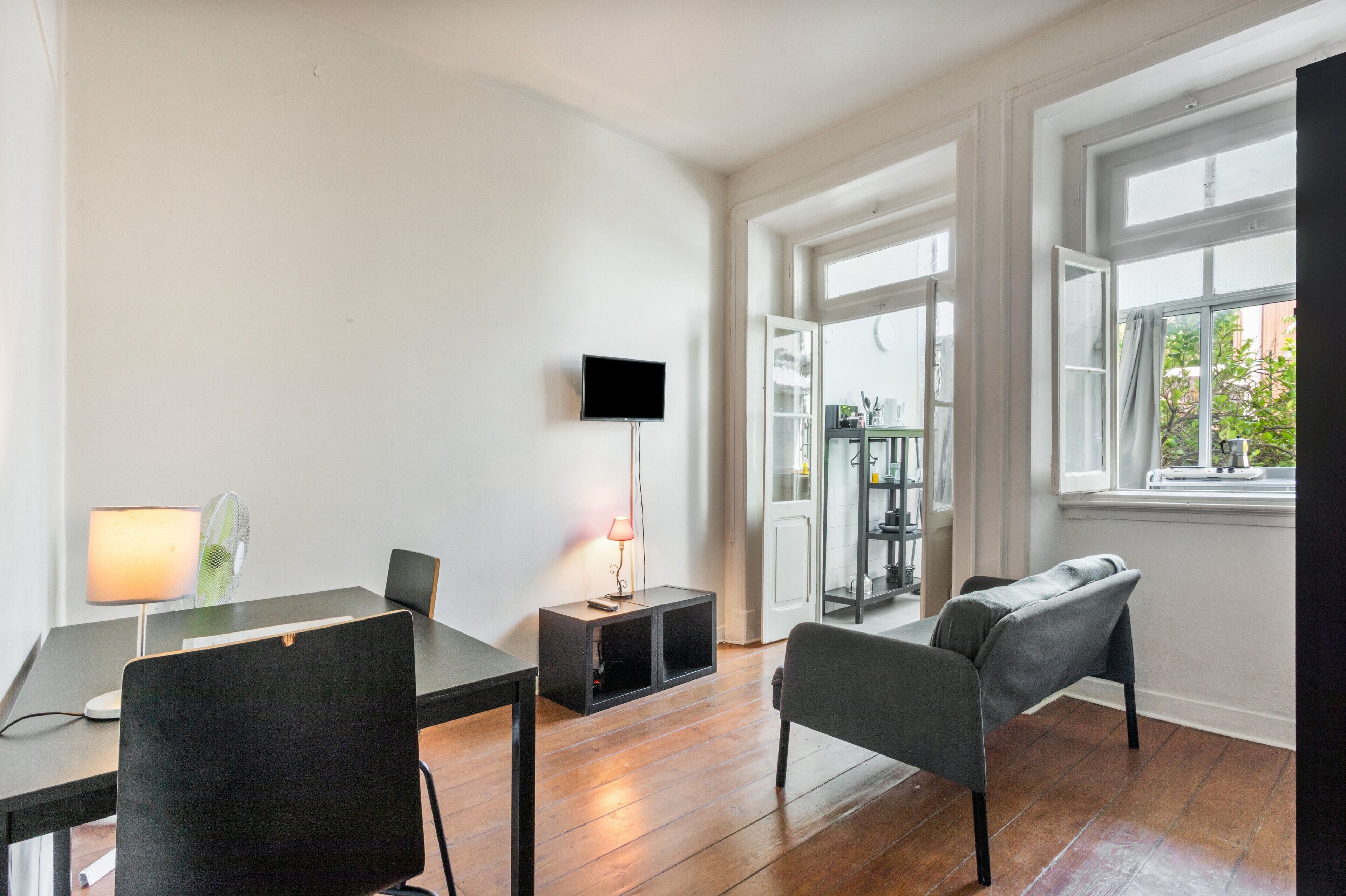 Een moderne woonkamer met een eettafel, stoelen, een televisie en een lamp.