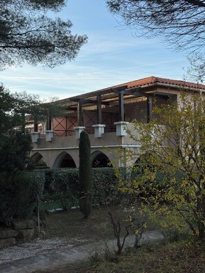 A building with a red-tiled roof, arched windows, and a covered walkway. - T2 luxury residence in a wooded park with 2 private pools and seafront (Saint-Raphaël)