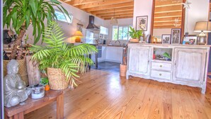 Una cocina amplia con vigas de madera, un comedor con banco, y un armario blanco con cajones.