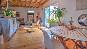 Amplia sala de estar con piso de madera, una mesa de comedor y un ventanal grande.