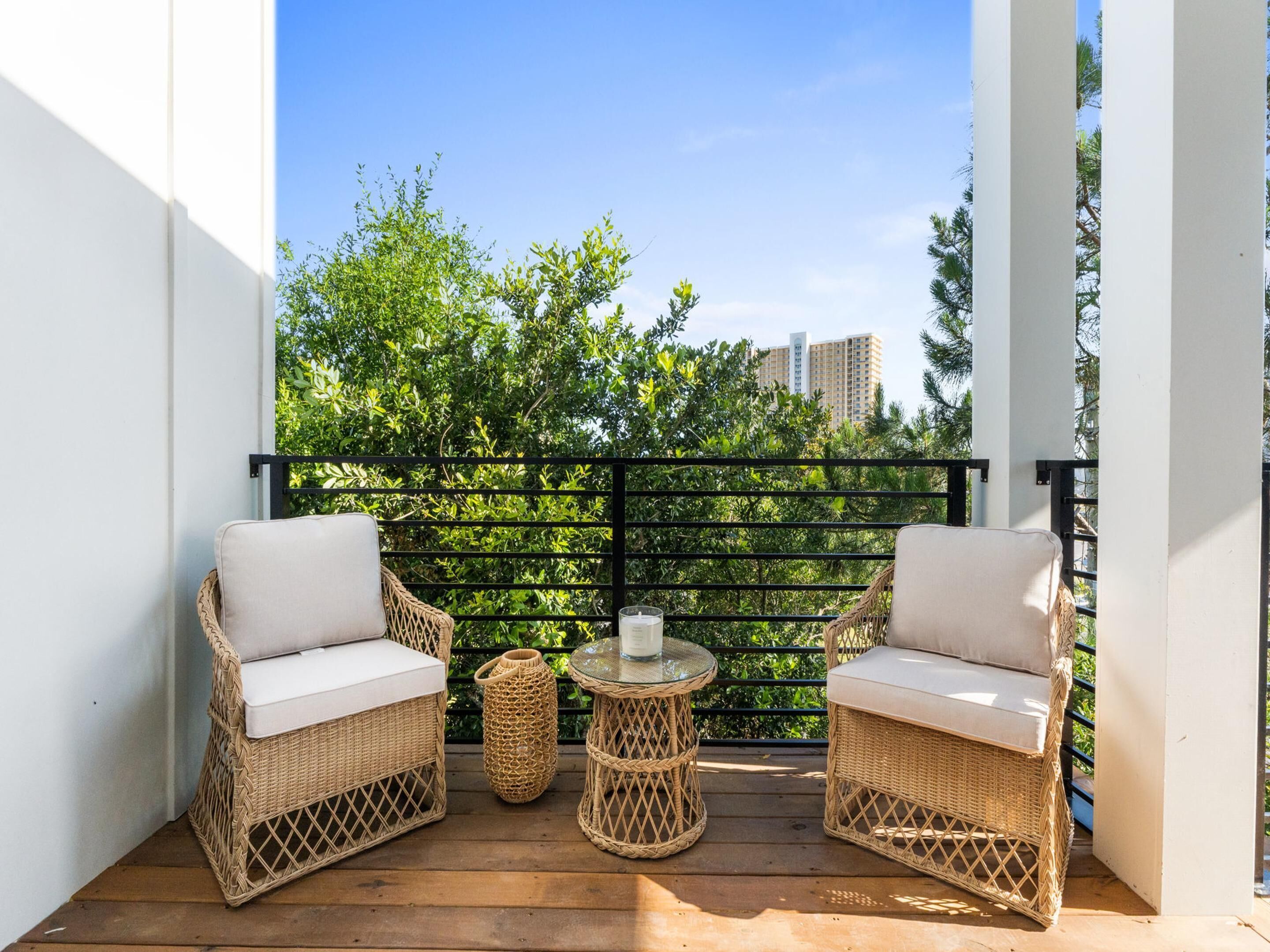 Ein Balkon mit Korbmöbeln, einem Glastisch und Blick auf Grünflächen und Gebäude.
