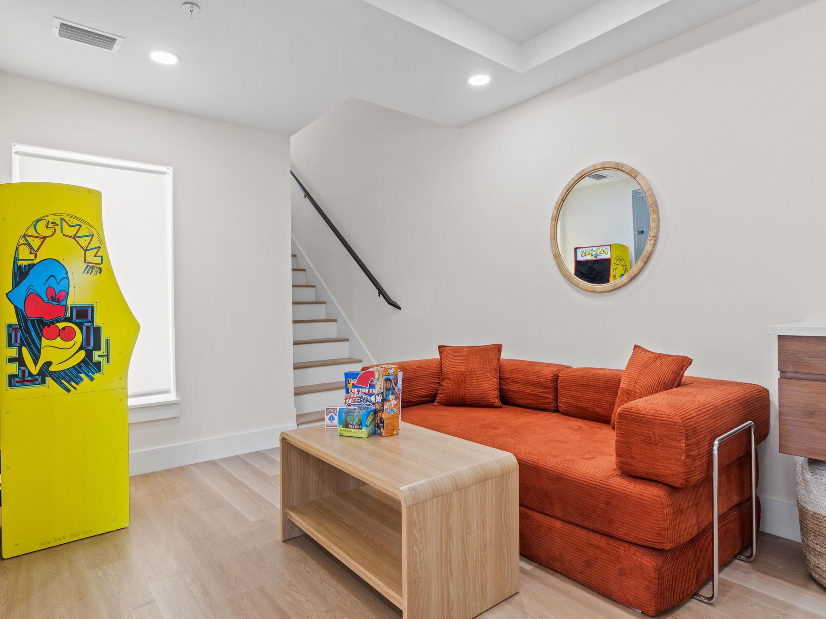 Ein modernes Wohnzimmer mit einer Couch, einem Couchtisch, einem Spiegel und einer Treppe.