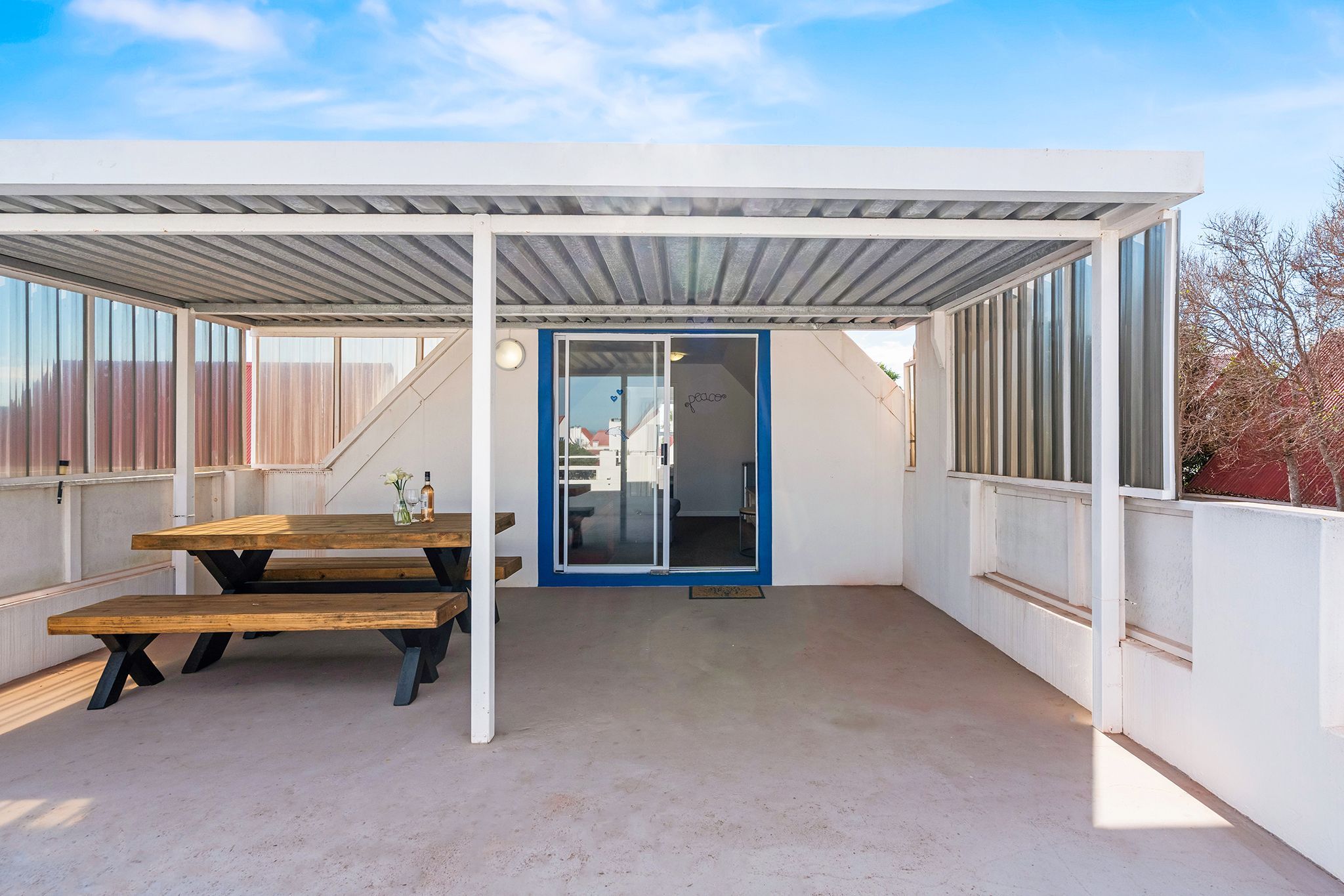 A covered outdoor area with a picnic table and a door leading to an interior space.