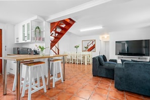 Eine moderne Küche mit weißen Schränken, einem Holzespeisetisch und einer Treppe.