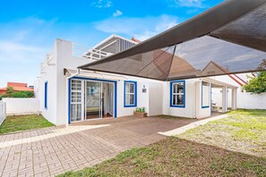 Ein modernes Haus mit überdachter Terrasse, Garage und kleinem Garten.