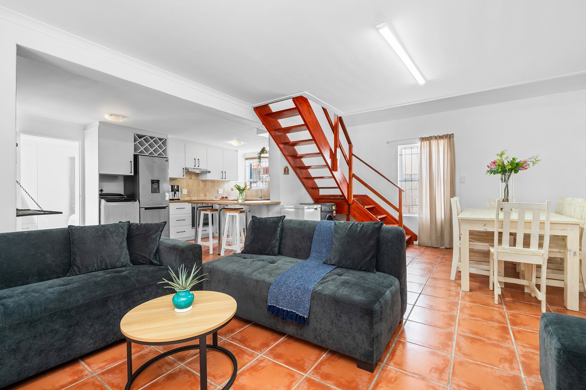 A modern living room with a sofa, coffee table, and a staircase.