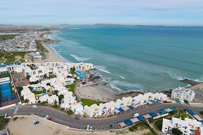 Une vue aérienne d’une ville côtière avec une plage, des bâtiments et une route.