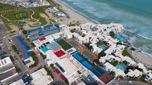 An aerial view of a coastal residential area with buildings, a beach, and a road. - Skal to 8 on Serifos (Langebaan)