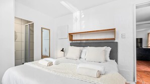 A modern hotel room with a large bed, a mirror, a bedside lamp, and a wooden shelf above the bed. - Skal to 8 on Serifos (Langebaan)