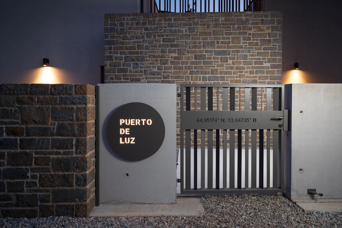 A gated entrance with a sign reading 'PUERTO DE LUZ' and coordinates.