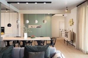 Una cocina moderna con una mesa de comedor, sillas, lámparas colgantes y un estante empotrado.