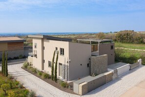 Una casa moderna de dos pisos con techo plano, fachada de piedra y camino de entrada de grava.