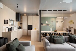 Una cocina moderna con armarios de madera, un comedor con mesa y sillas, y una sala de estar con sofá.