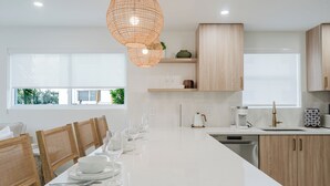 Een moderne keuken met een groot kookeiland, houten stoelen en hanglampen.