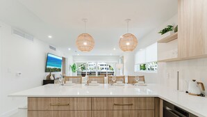 Een moderne keuken met een groot schiereiland, hanglampen en uitzicht naar buiten.