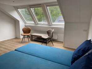 Een kamer met een bed, twee stoelen, een tafel en een dakraam.