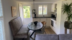 A compact kitchen with a dining area, a bench, and a potted plant. - Eendje 2 | Luxe vakantiehuis met hottub | Ermelo, Veluwe (Ermelo)