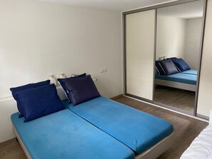 Een kamer met een bed, een spiegel en een kledingkast.