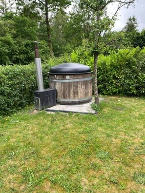 Une structure cylindrique extérieure, dotée d’une cheminée, entourée d’herbe et d’arbres.