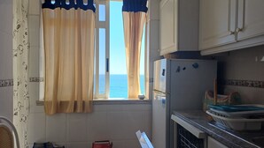 Una cocina con vista al mar, un refrigerador y un lavamanos.