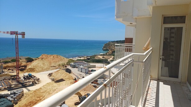 Un balcón con vista al mar y a una zona de construcción.