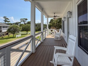 A covered porch with white railings, a ceiling fan, and two rocking chairs.