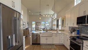 Una cocina moderna con electrodomésticos de acero inoxidable, armarios blancos y una isla central.