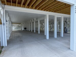 A covered parking area with white pillars and a concrete floor.