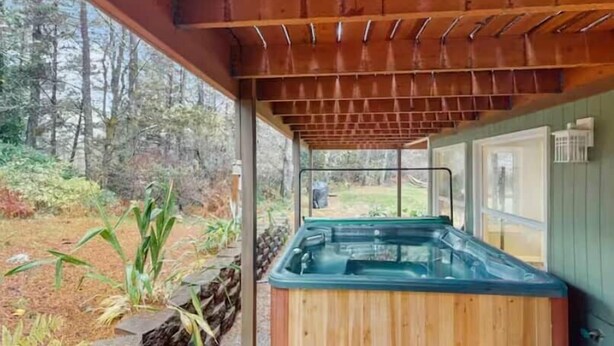 Ein Whirlpool unter einer Holzpergola mit Blick auf ein bewaldetes Gebiet.