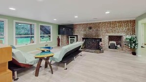 Ein geräumiges Wohnzimmer mit Kamin aus Ziegelsteinen, einer Couch, einem Couchtisch und einem Fernseher.