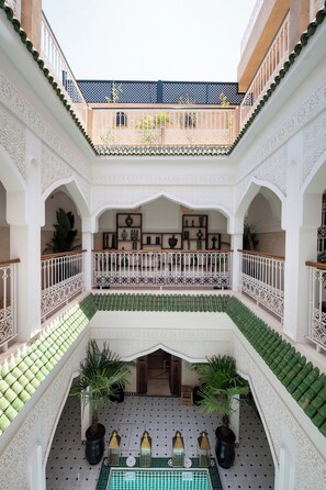 A multi-level courtyard with ornate railings, potted plants, and a checkered floor pattern.