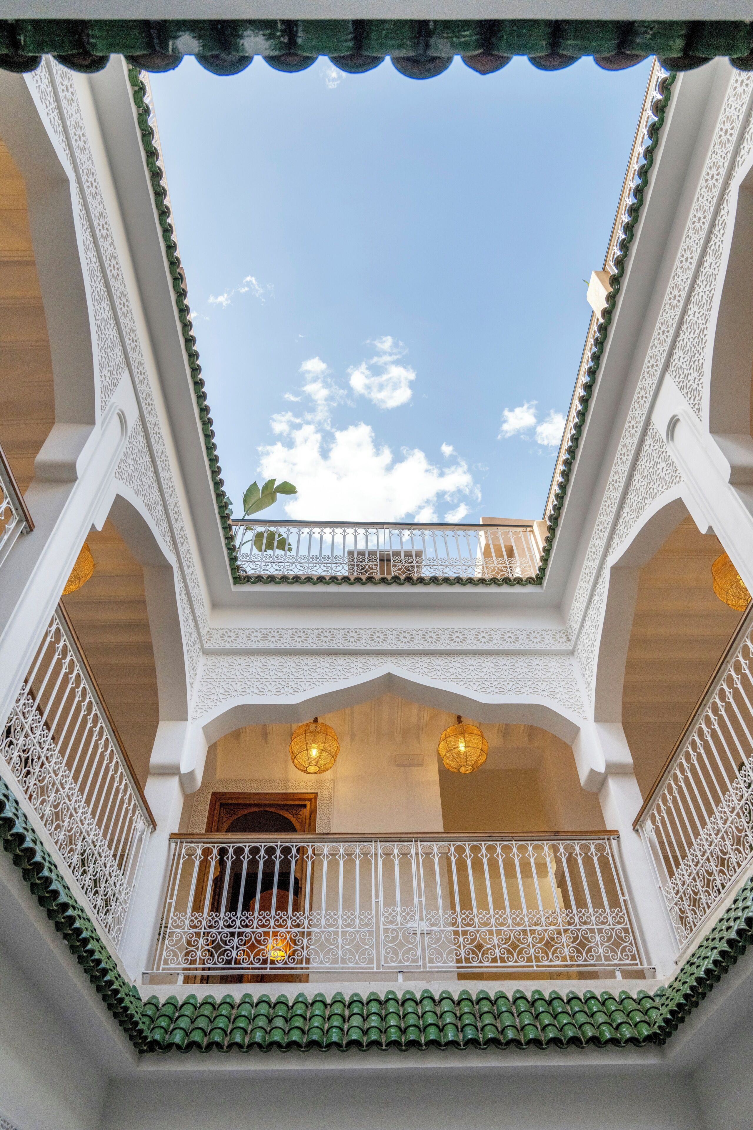 A multi-level atrium with ornate white railings, green-tiled roofs, and hanging lanterns.