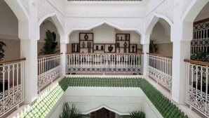 A multi-level courtyard with ornate white railings, green tiled flooring, and decorative plant arrangements. - Bab Akoul Medina & spa (Marrakech)