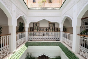 A multi-level courtyard with ornate white railings, green tiled flooring, and decorative plant arrangements. - Bab Akoul Medina & spa (Marrakech)