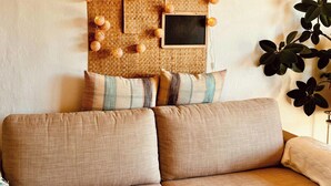 Ein Sofa mit gemusterten Kissen, einer gewebten Wanddekoration und einem Blumentopf.
