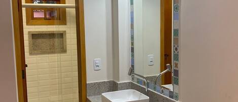 A bathroom with a toilet, sink, mirror, and towel rack.