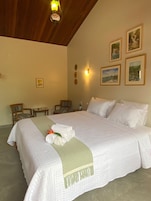 Habitación de hotel con una cama grande, dos sillas, una mesita y una obra de arte en la pared.