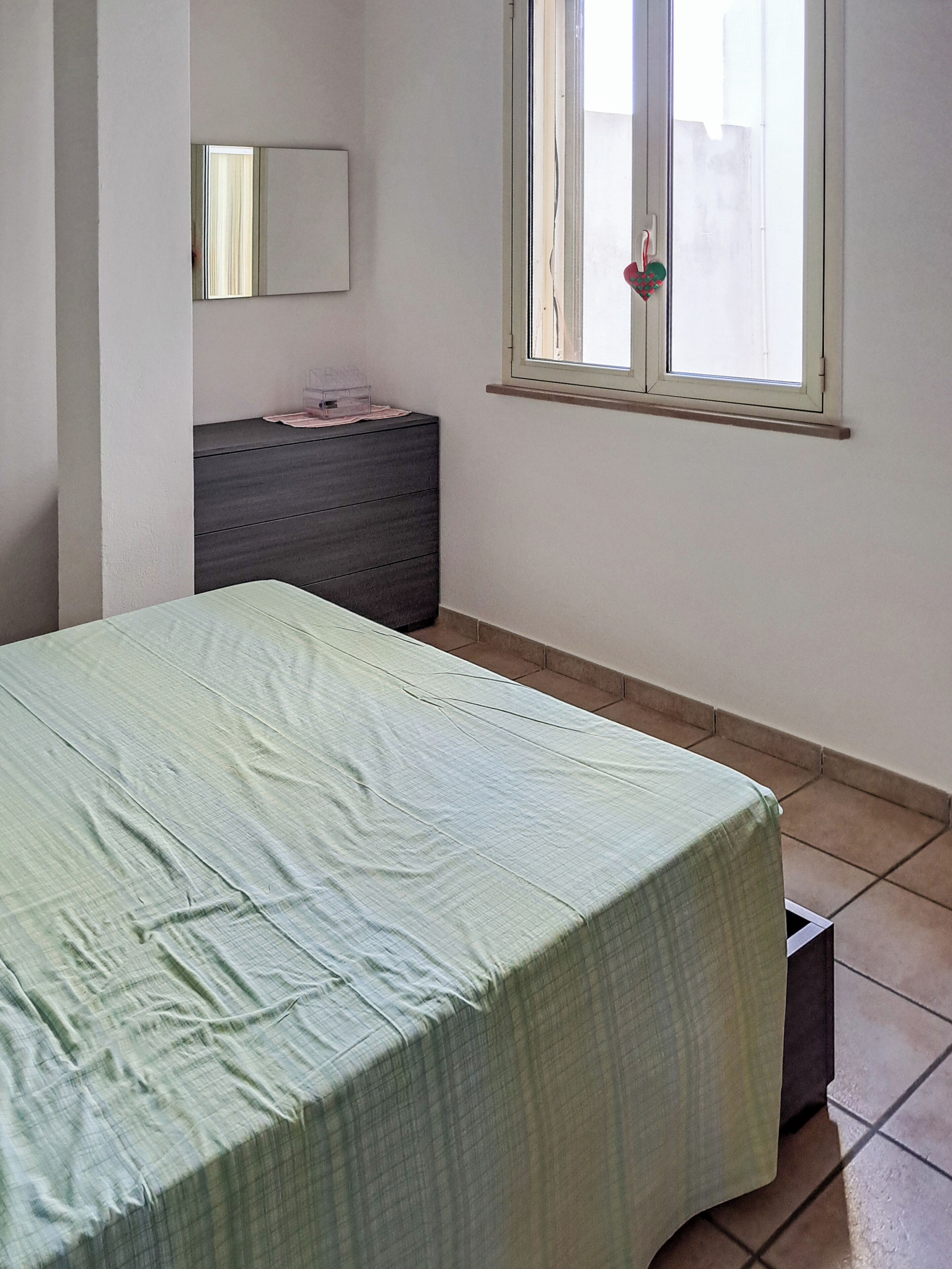 A room with a bed, a dresser, a window, and a mirror.