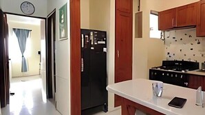 A kitchen with a refrigerator, stove, and a white countertop. - Martina Caribbean II Ocean View Apt • 2BR Apartment Near Malecón (Santo Domingo)