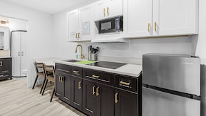 A modern kitchen with white cabinets, a stainless steel refrigerator, and a microwave. - Veras Inn & Suites (Fort Myers)