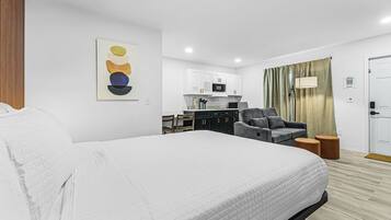 Quarto de hotel com cama, escrivaninha, cadeira, sofá, micro-ondas e porta.