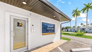 A hotel entrance with a glass door, a signboard, and a parking area. - Veras Inn & Suites (Fort Myers)