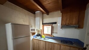 A kitchen with wooden cabinets, a white refrigerator, a microwave, and a gas stove.