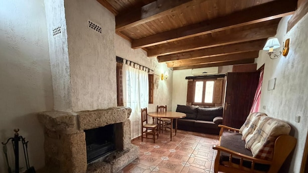A rustic interior with a stone fireplace, wooden furniture, and a tiled floor.