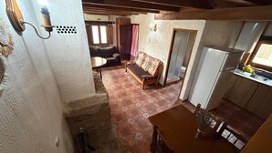 A rustic interior with a dining area, kitchen, and living space with a sofa and a table.