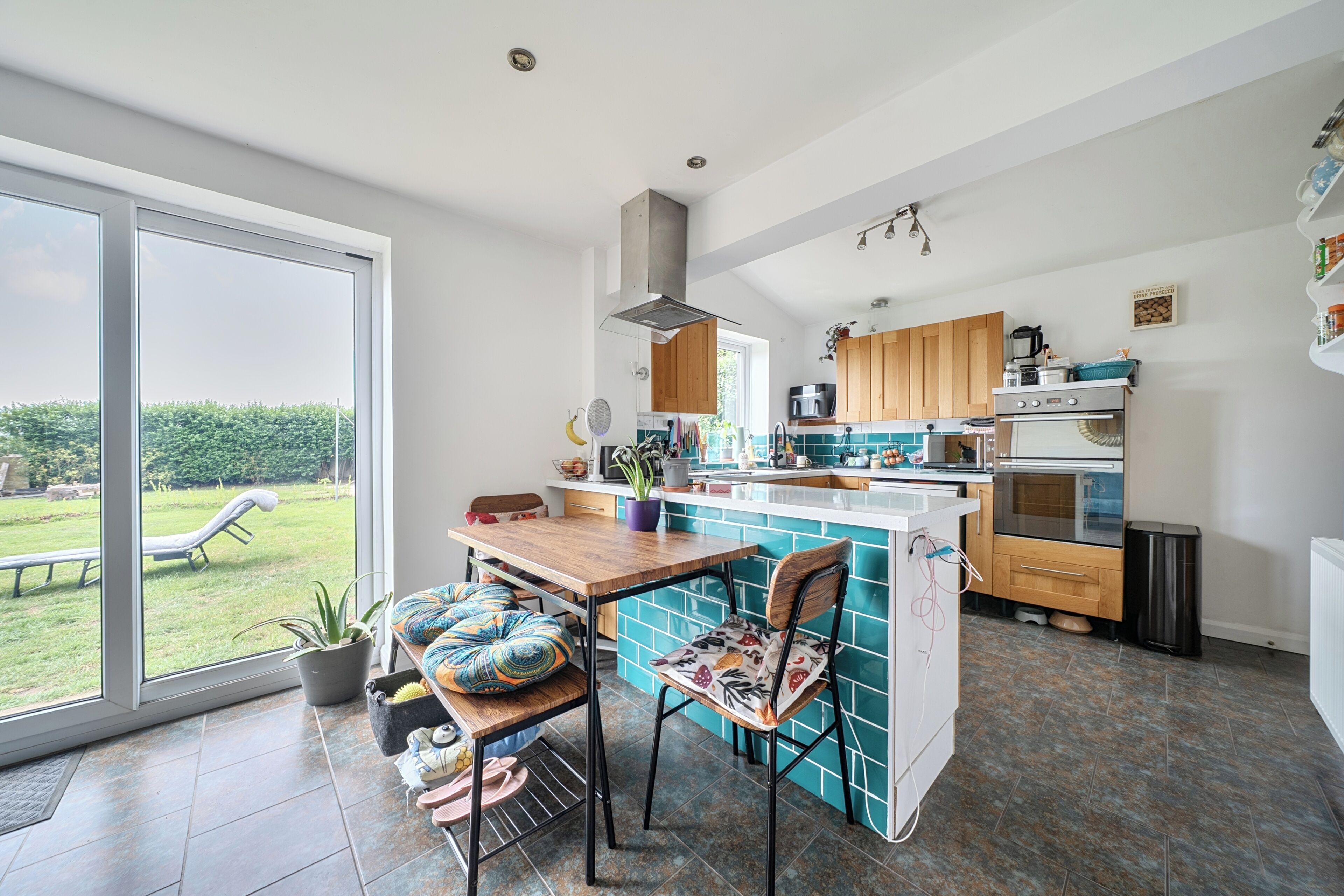 A modern kitchen with a large island, wooden cabinets, and a view to the outdoors.