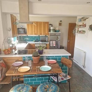 Cocina compacta con armarios de madera, una isla central y un comedor con mesa y sillas.