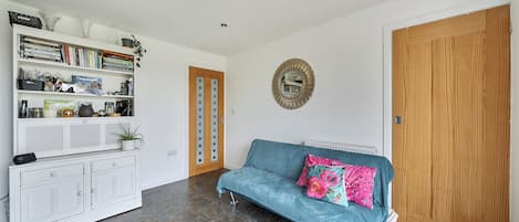 A living room with a blue sofa, a white cabinet, and a wooden door.
